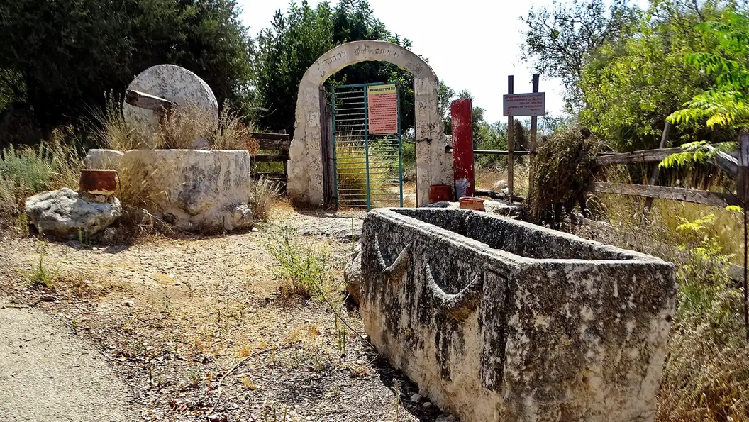 A stone trough, a millstone and an arched gateway at Kfar Hashmonai, the reconstructed ancient village at Shilat